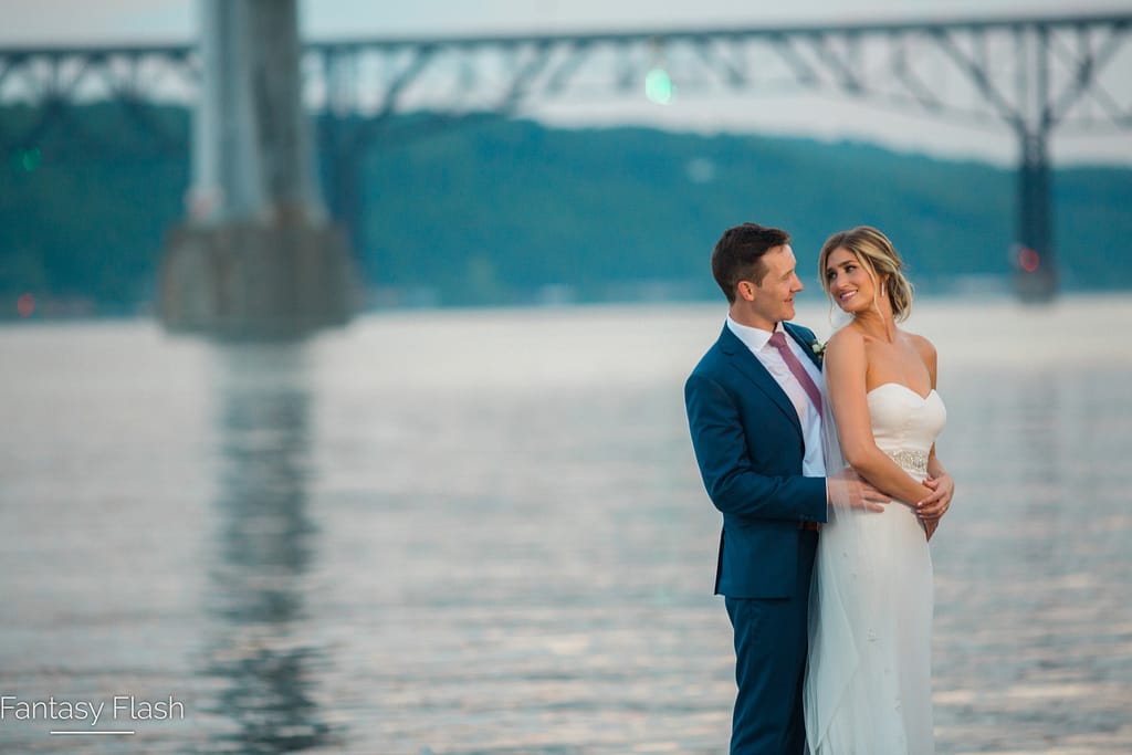 A newlywed couple posing near the Hudson River