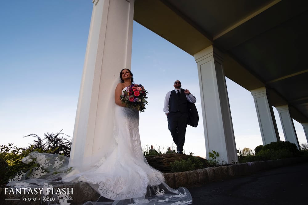 A bride and groom standing under the covered patio at New York Country Club