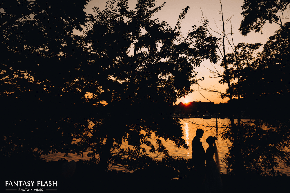 A silhouette of a bride and groom by the water