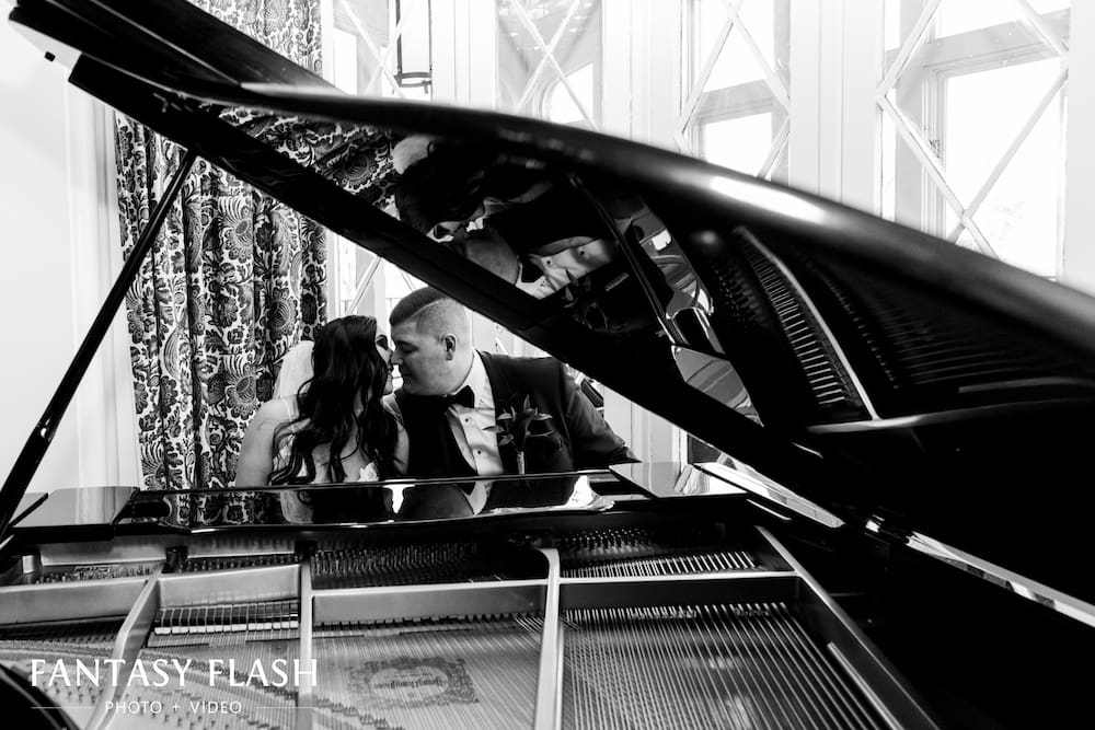 a bride and groom sitting at a grand piano